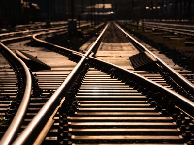 Railway track panorama and switches at station in Sauerland Germany with geometrical structure and vanishing point. Warm evening sunlight reflected by bright steel surface, screws and thresholds.
